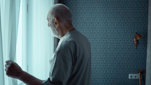 Persona mayor mirando por la ventana, símbolo del aislamiento social y la soledad en la vejez